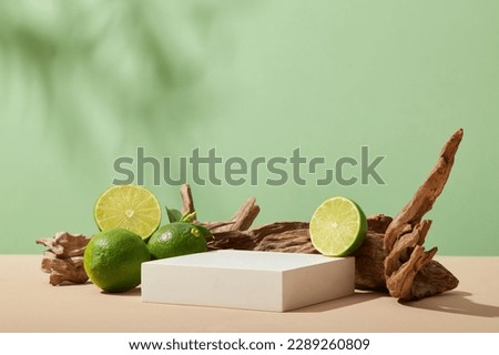 An empty white rectangle podium displayed with Limes and tree branch on pastel background with tropical leaves shadow. Blank space to show beauty product extracted from Lime (Citrus aurantiifolia)