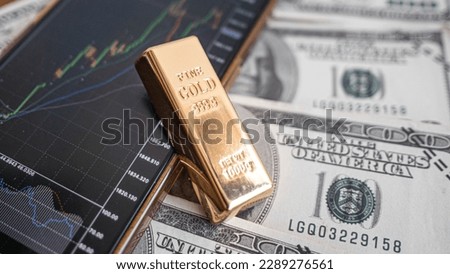 gold bars place on the phone that opens the candlestick chart. and dollar. Fluctuations in gold prices concept. Royalty-Free Stock Photo #2289276561