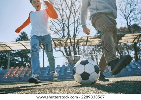 Father and Son play football on stadium, Happy family outdoors, bonding, family fun, players in soccer in dynamic action have fun playing football in sunny day, holidays time.