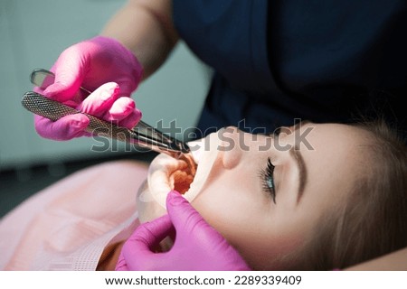 Doctor dentist pulls out a tooth to a patient in a hospital. Disposable rubber mouth opener. Royalty-Free Stock Photo #2289339409