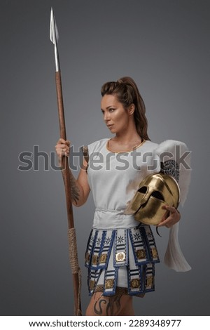 Portrait of isolated on grey background greek soldier woman with spear.