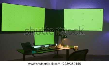 Studio with modern equipment for video or film color grading. Computer, digital tablet and big screens showing program interface, video footage. Color correction control panel. Green screen, chromakey