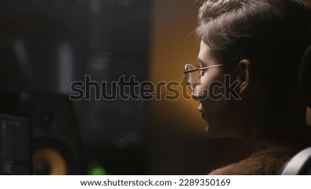 Close up shot of female editor makes color grading for video or film on computer in modern studio. Young woman edits photo, develops design project, plays video game. Big digital screen on background.