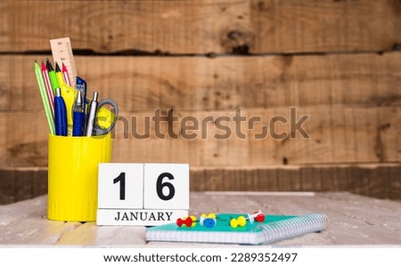 January calendar background with number  16. Stationery pens and pencils in a case on a wooden vintage background. Copy space notepad with pencils and a calendar. Planner place for text.