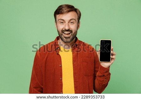 Elderly man 40s years old he wears casual clothes red shirt t-shirt hold in hand use mobile cell phone with blank screen workspace area isolated on plain pastel light green background studio portrait