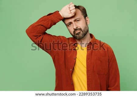 Elderly ill sick sad caucasian man 40s years old he wearing casual clothes red shirt t-shirt put hand on forehead suffer from headache isolated on plain pastel light green background studio portrait