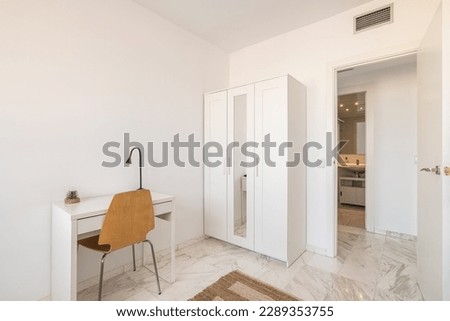 Cozy interior in white tones with wardrobe and table and chair with open door to the bathroom. Concept of a bright new fresh interior in the apartment Royalty-Free Stock Photo #2289353755
