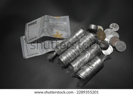 rupiah banknotes and coins with large numbers and a black background