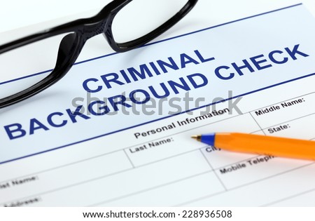Criminal background check application form with glasses and ballpoint pen.