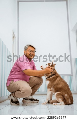a male vet playing with brown siberian dog and smiling