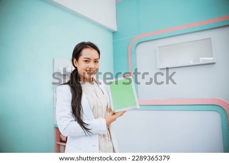 female vet with pony tail showing tablet on her hand and smiling against her assistant at the background