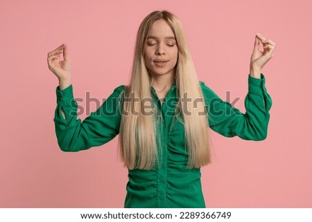 Keep calm down, relax, inner balance. Young caucasian woman breathes deeply with mudra gesture, eyes closed, meditating with concentrated thoughts, peaceful mind. Girl isolated on pink background