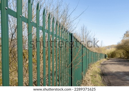 green Palisade security Fencing against a bright blue sky Royalty-Free Stock Photo #2289371625