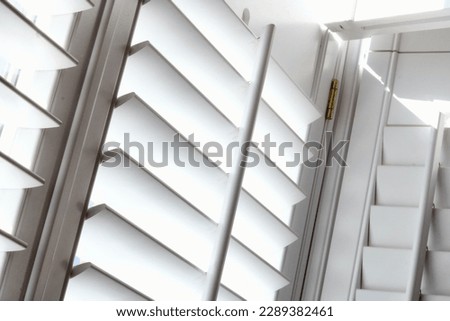 Angled full frame image of light shining through plantation shutters Royalty-Free Stock Photo #2289382461