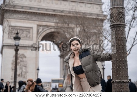 Woman tourist on background of famous Arc de Triomphe. Winter or autumn in Europe. Paris, France.