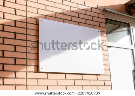 white rectangle logo on brick wall building exterior for mockup design, shadow overlay