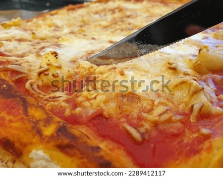 a taqty close up portrait of a piece of delicious pineapple pizza ready to be cut by a sharp knie into pieces to be eaten.