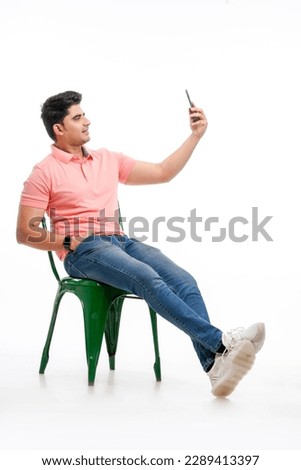 Young indian man taking selfie in smartphone.