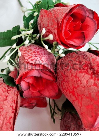 Red plastic roses are still buds, which people usually use for wall decoration