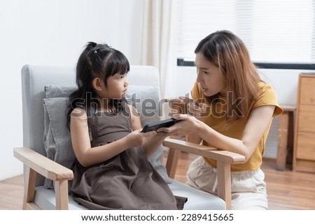 Asian mother grab mobile phone from her daughter for stop her daughter from game addiction. Royalty-Free Stock Photo #2289415665