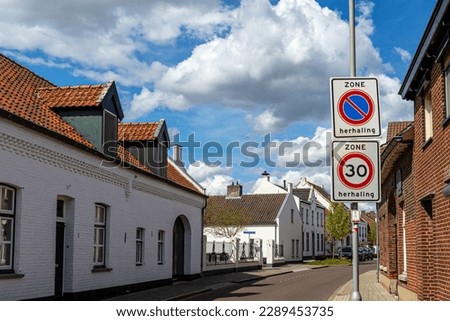 Architectural landscape of street with traffic signs against blue sky with clouds, 30 km zone and No parking, houses with white walls, sunny day in Thorn old Dutch town in Midden-Limburg, Netherlands