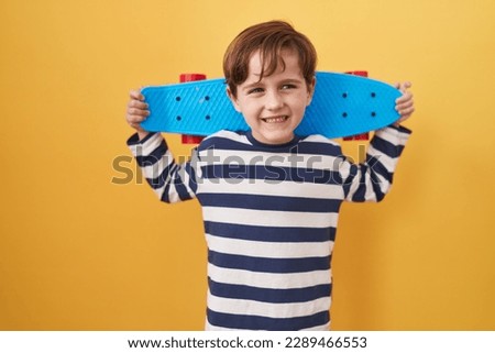 Little caucasian boy holding skate over yellow background celebrating crazy and amazed for success with open eyes screaming excited.  Royalty-Free Stock Photo #2289466553