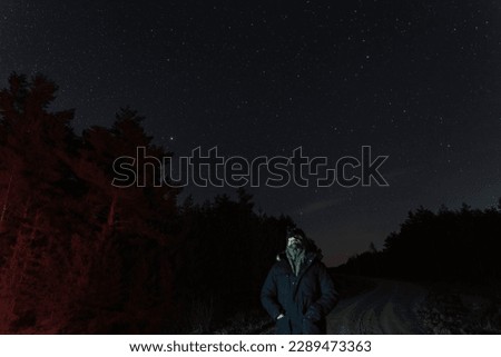 Night scene, soft focus photo, main focus on the starry sky.  A man with a night vision device watches the stars in the forest.