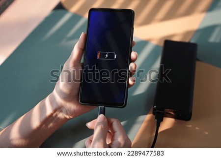 Woman hands plugging the charger into smart phone at the coffee shop Royalty-Free Stock Photo #2289477583