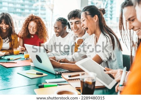 Multiracial university students sitting together at table with books and laptop - Happy young people doing group study in high school library - Life style concept with guys and girls in college campus Royalty-Free Stock Photo #2289480315