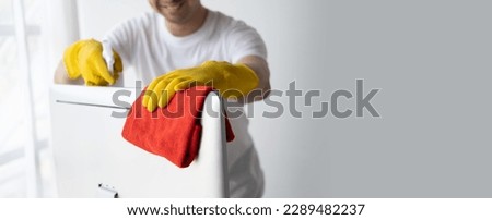 Close up view of man cleaning desktop computer using clothes. Cleaning office desk concept.