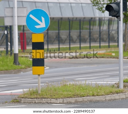 Close-up photo of a Blue Direction traffic sign placed on a traffic island