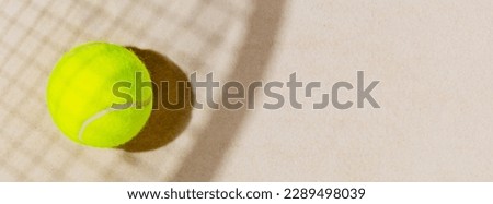Tennis banner with tennis yellow ball on the sand beach with racket  shadow. Tennis competitions, healthy sport and outdoor activities concept. Flat lay, banner size, copy space