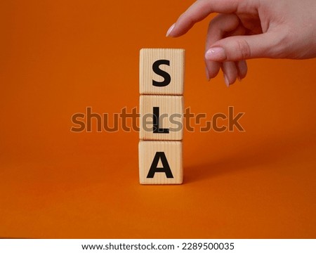 SLA - Service Level Agreement. Wooden cubes with word SLA. Businessman hand. Beautiful orange background. Business and Service Level Agreement concept. Copy space.
