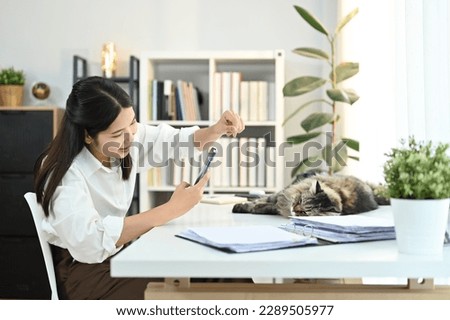 Positive moment young woman take a picture with her cat in the office.