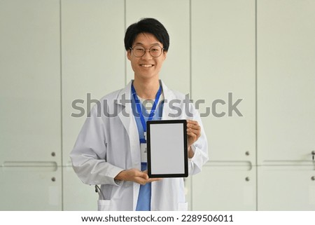 Doctor wearing white uniform showing digital tablet with blank screen for advertisement. Telehealth online applications concept