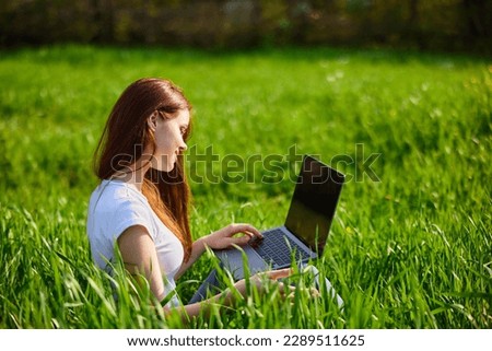 Portrait of beautiful young woman on nature with laptop Royalty-Free Stock Photo #2289511625