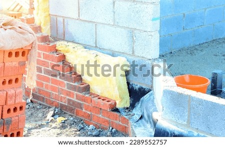 Insulating walls of new build houses by placing rock wool inside wall cavities as part of the energy-saving measures. House insulated with mineral wool to reduce energy bill Royalty-Free Stock Photo #2289552757