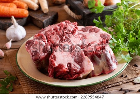 Pieces of raw oxtail and spices for cooking on a wooden board on the wooden table
