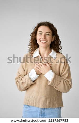 Happy pleased pretty young woman holding hands on chest feeling gratitude, mental balance, expressing thanking, kindness and love in heart standing isolated at white background. Royalty-Free Stock Photo #2289567983