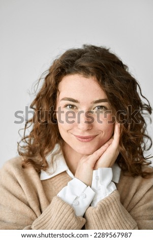 Young smiling pretty curly woman, happy beautiful feminine girl looking at camera isolated at white background, advertising products and services, close up face vertical headshot portrait.