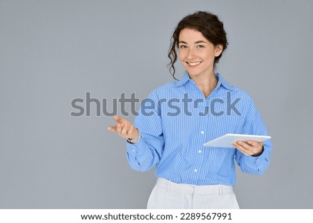 Young smiling professional business woman office worker executive holding digital tablet presenting corporate web service standing isolated at grey advertising online education, business training.