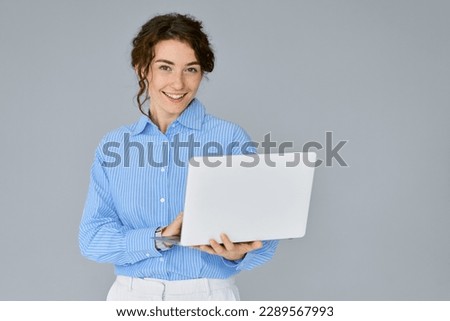 Young happy business woman professional executive hr manager using laptop advertising web service, holding computer searching job online on website standing isolated on gray background, studio shot.