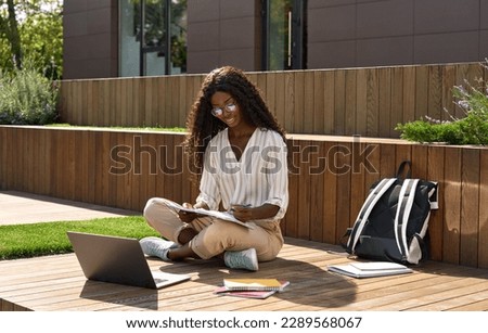 African girl student learning online using laptop studying outside campus. Pretty black young woman model elearning using laptop computer on sunny day, remote virtual learning, watching online webinar