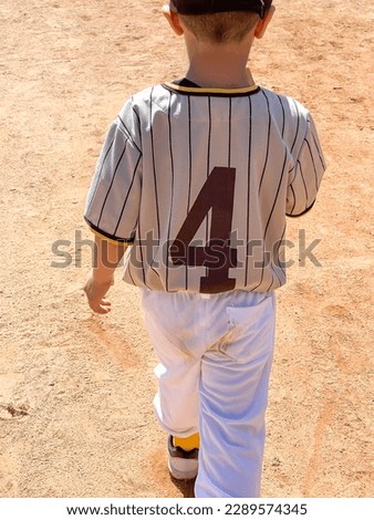 View of a young boy from behind with filthy pants while playing tee ball. Dirt stain on white sport pants.