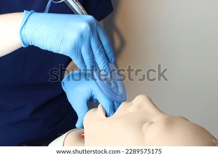 Laryngeal mask airway (LMA) Bering inserted in a simulated patient airway by a health care professional wearing gloves and surgical scrubs  Royalty-Free Stock Photo #2289575175