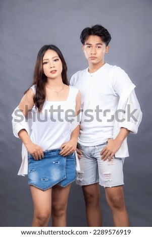 elegant men and women are posing standing in front of the camera with their shirts open, their hands to their waists facing forward in an indoor setting. fashion promotion couple photo session in stud