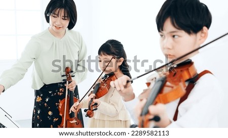 Children learning the violin.
 Music class. Royalty-Free Stock Photo #2289582113