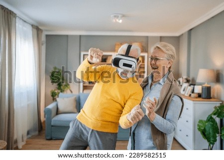 man mature senior caucasian male husband with his wife senior couple at home enjoy virtual reality VR headset Royalty-Free Stock Photo #2289582515