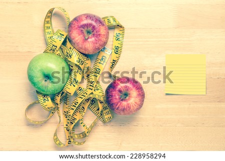 apple and a measuring tape on wooden table with label