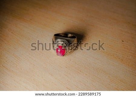 Close-up of a luxurious pink gemstone ring against a modern wooden backdrop